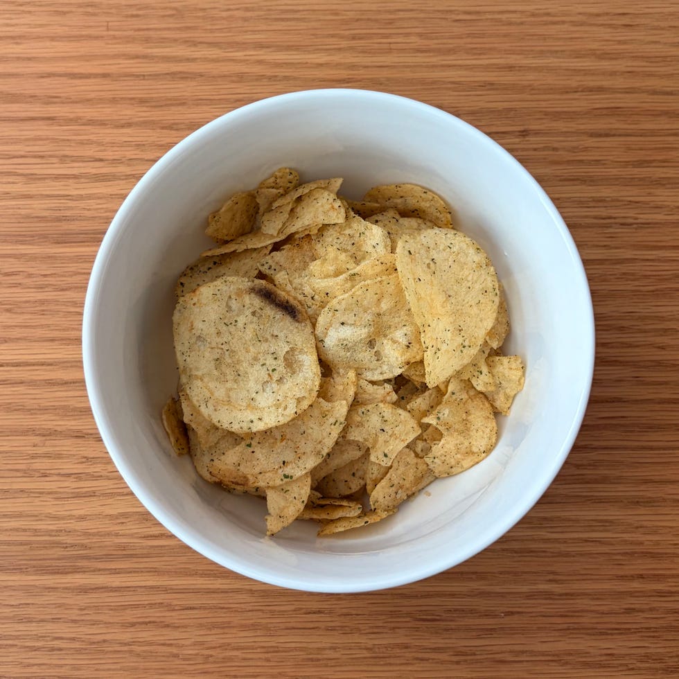 Bowl filled with potato chips on a wooden table.