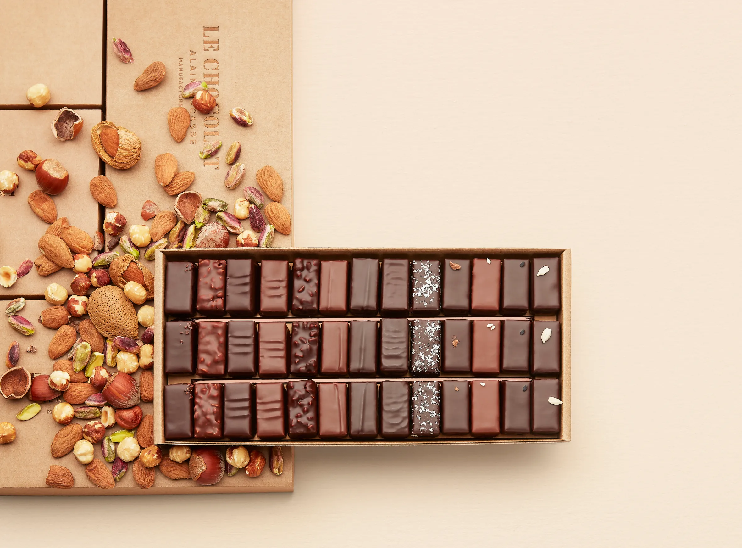 Alain Ducasse chocolates in a box, surrounded by nuts.