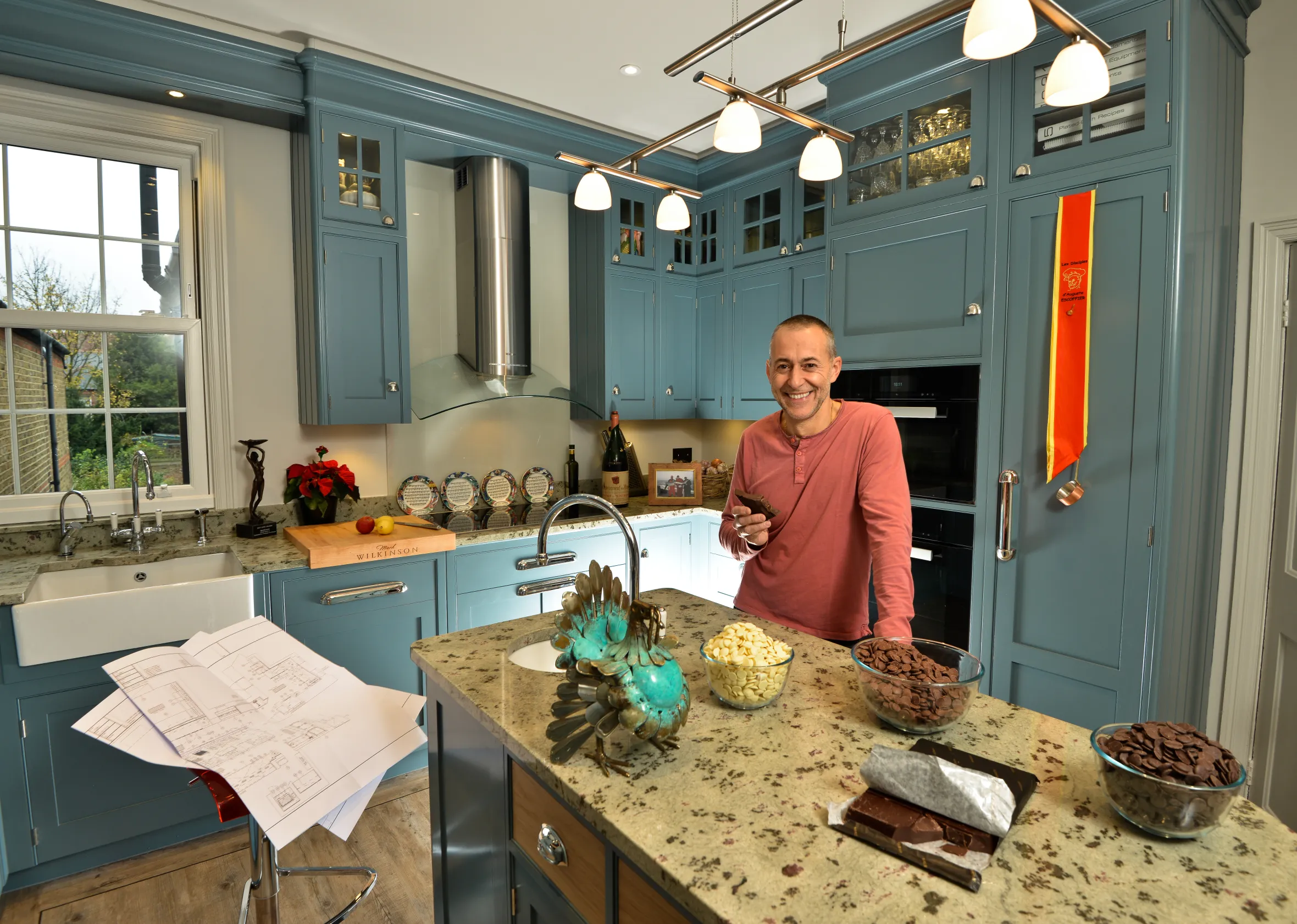 Michel Roux Jr. stands in his kitchen, holding a bar of chocolate.
