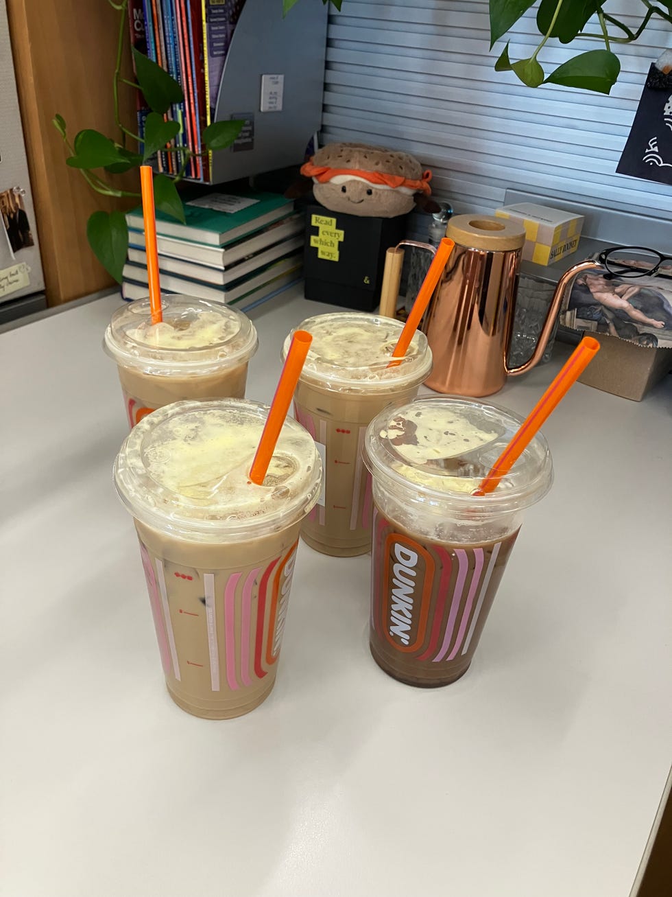 Four iced coffee beverages placed on a desk.