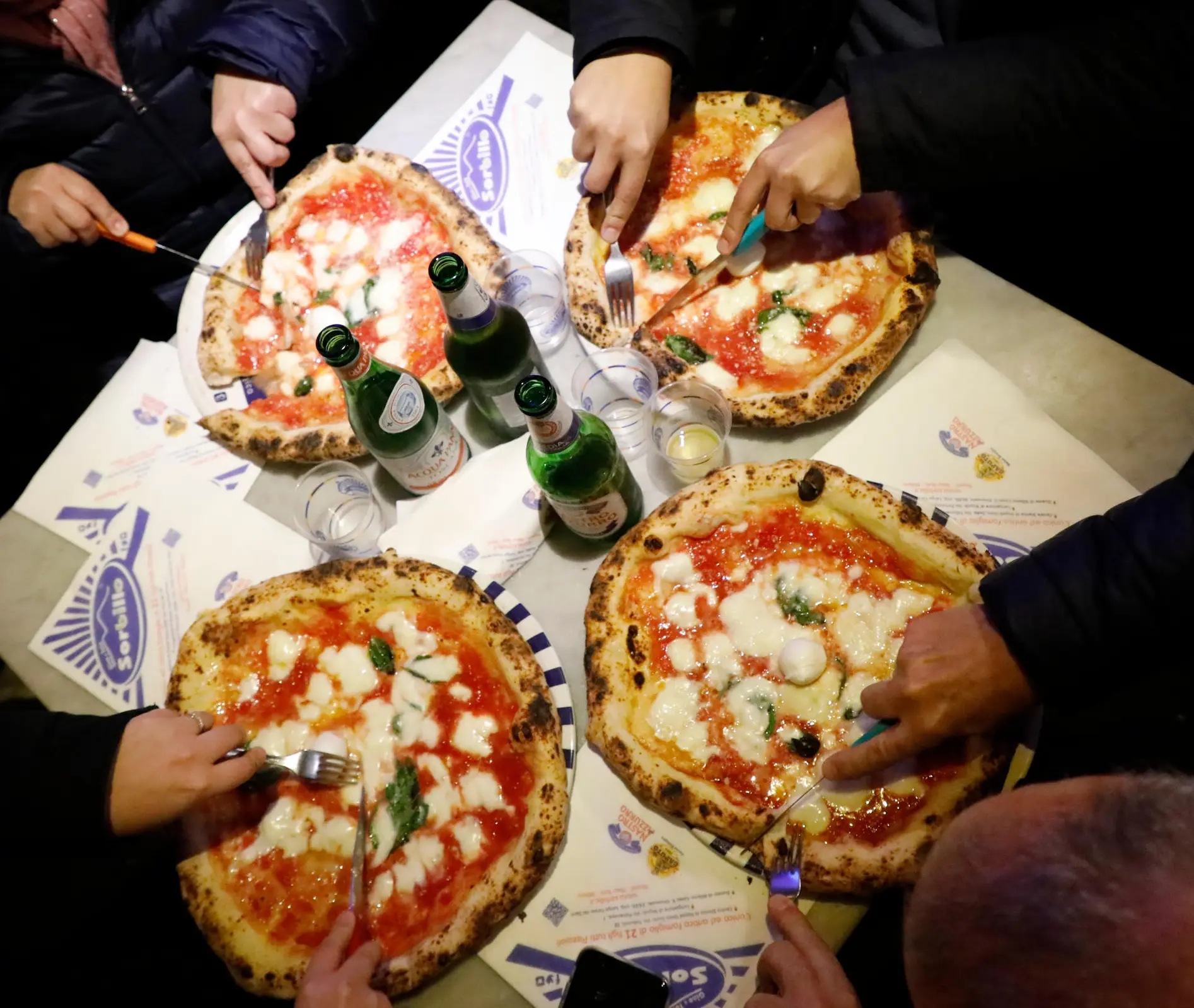People sharing pizzas at the reopened Gino Sorbillo pizzeria.