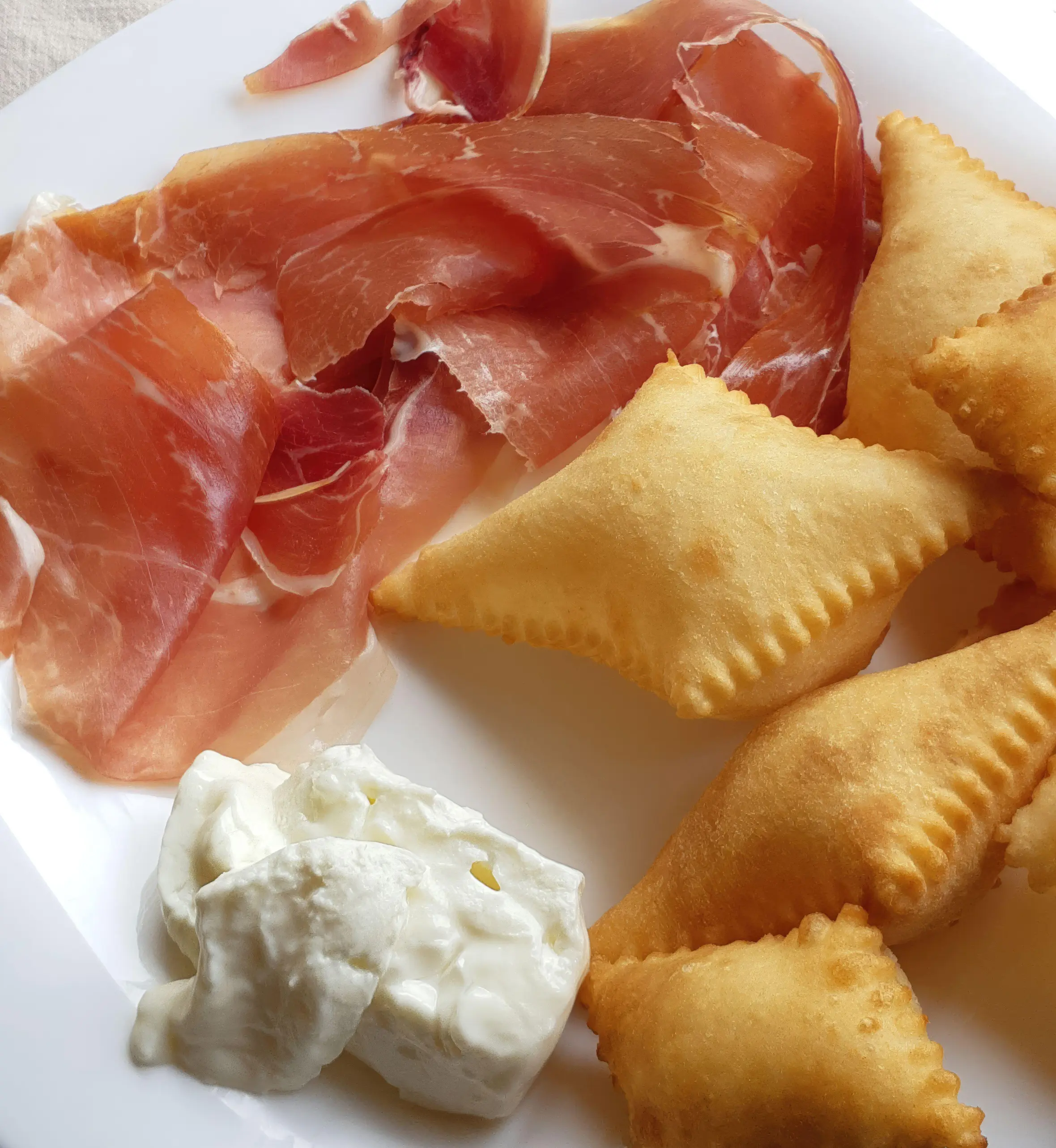 Italian dish with crescentine, prosciutto crudo, and squacquerone cheese.