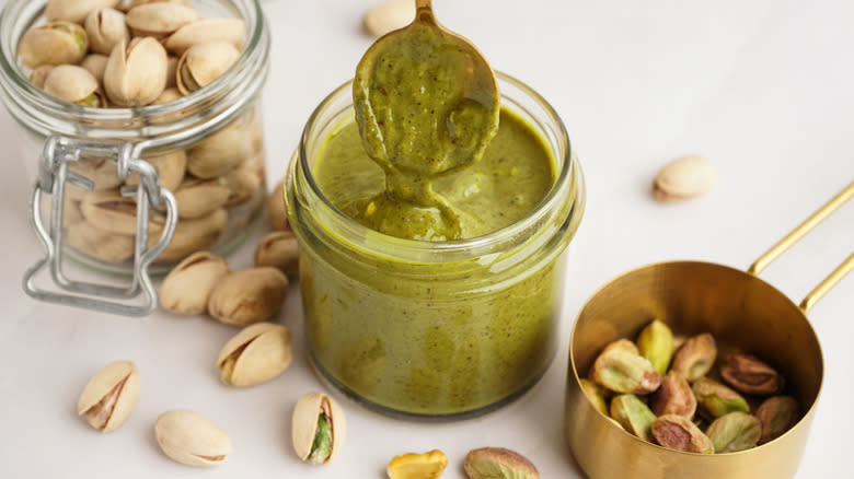 Jar of pistachio butter beside whole pistachios