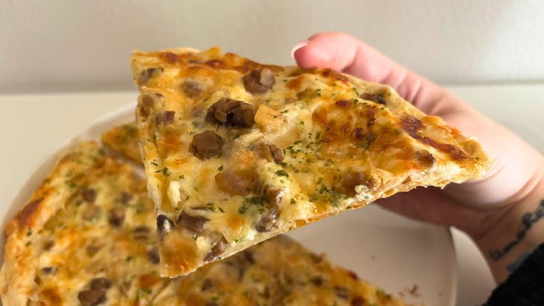 Hand holding a slice of Trader Joe's Tarte aux Champignons