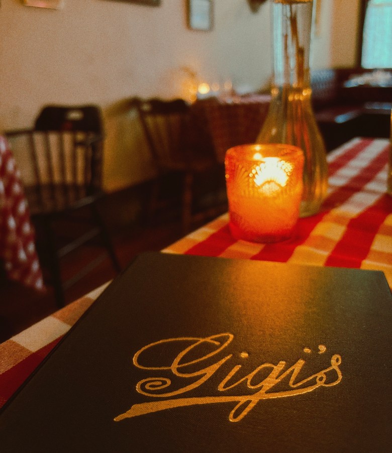 Gigi's restaurant menu on candlelit table with red-checked tablecloth in cozy Atlanta dining room