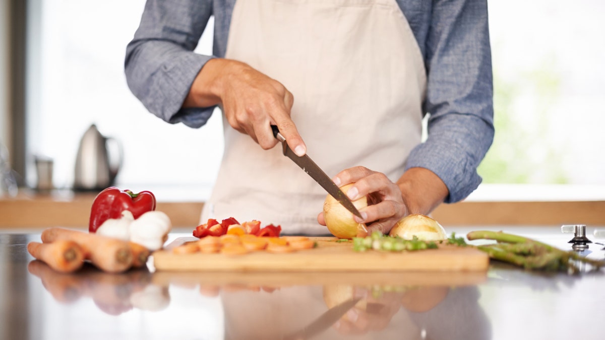 A man chopping vegetables on a cutting board.
