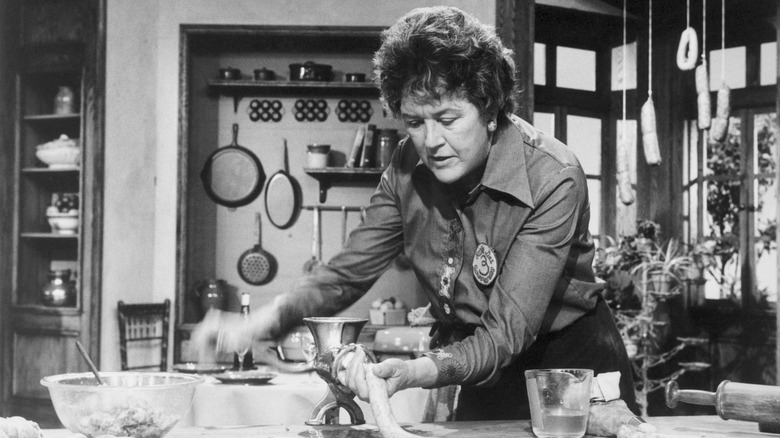 black and white photo of Julia Child using sausage grinder in her kitchen