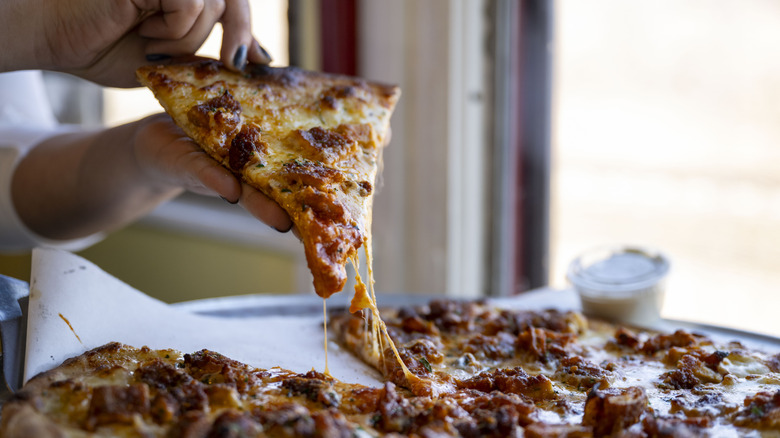 Hands lifting a slice of pizza