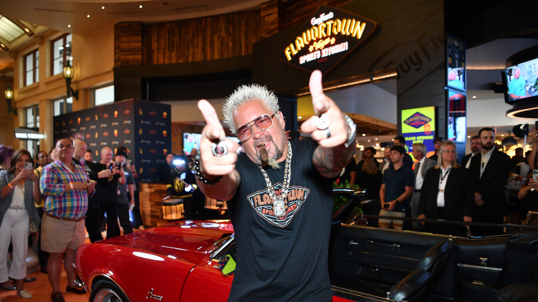 Guy Fieri poses in front of his iconic car, with the 