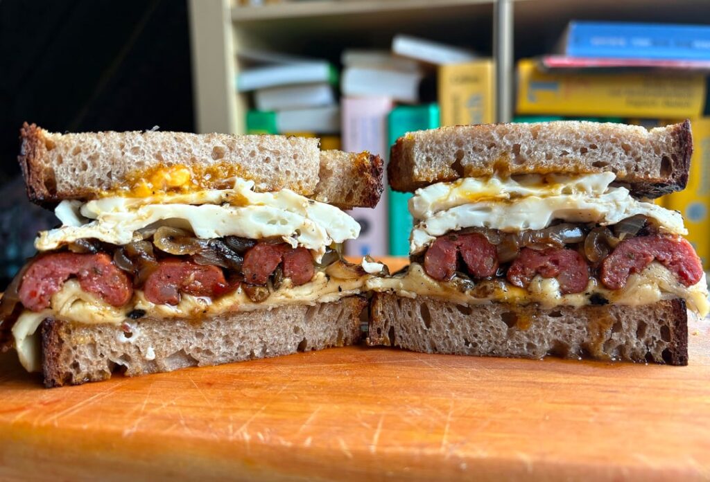 Panino con salsiccia, formaggio, cipolla e uova