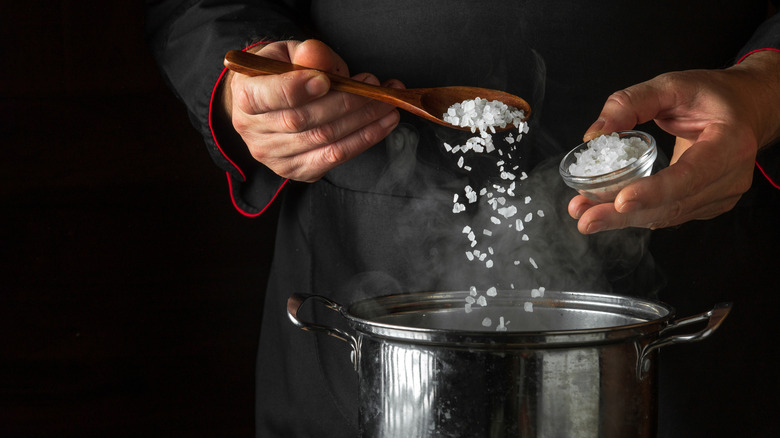 Chef adding salt to a pot