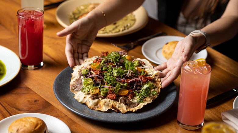 A person putting a tlayuda on a table at a restaurant in Oaxaca