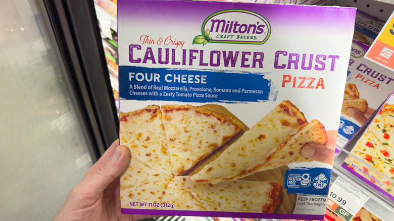 Box of Milton's frozen pizza being held up in a store