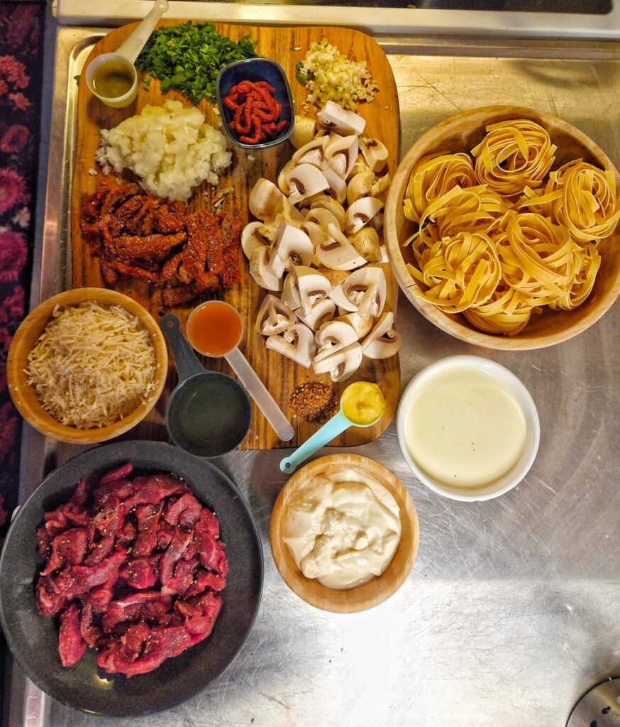 Pasta with shredded sirloin, garlic, onion, tomato paste, sun-dried tomatoes, white wine, cream, crème fraîche, veal stock, Dijon mustard, chili flakes, mushrooms, parsley, truffle oil, and parmesan