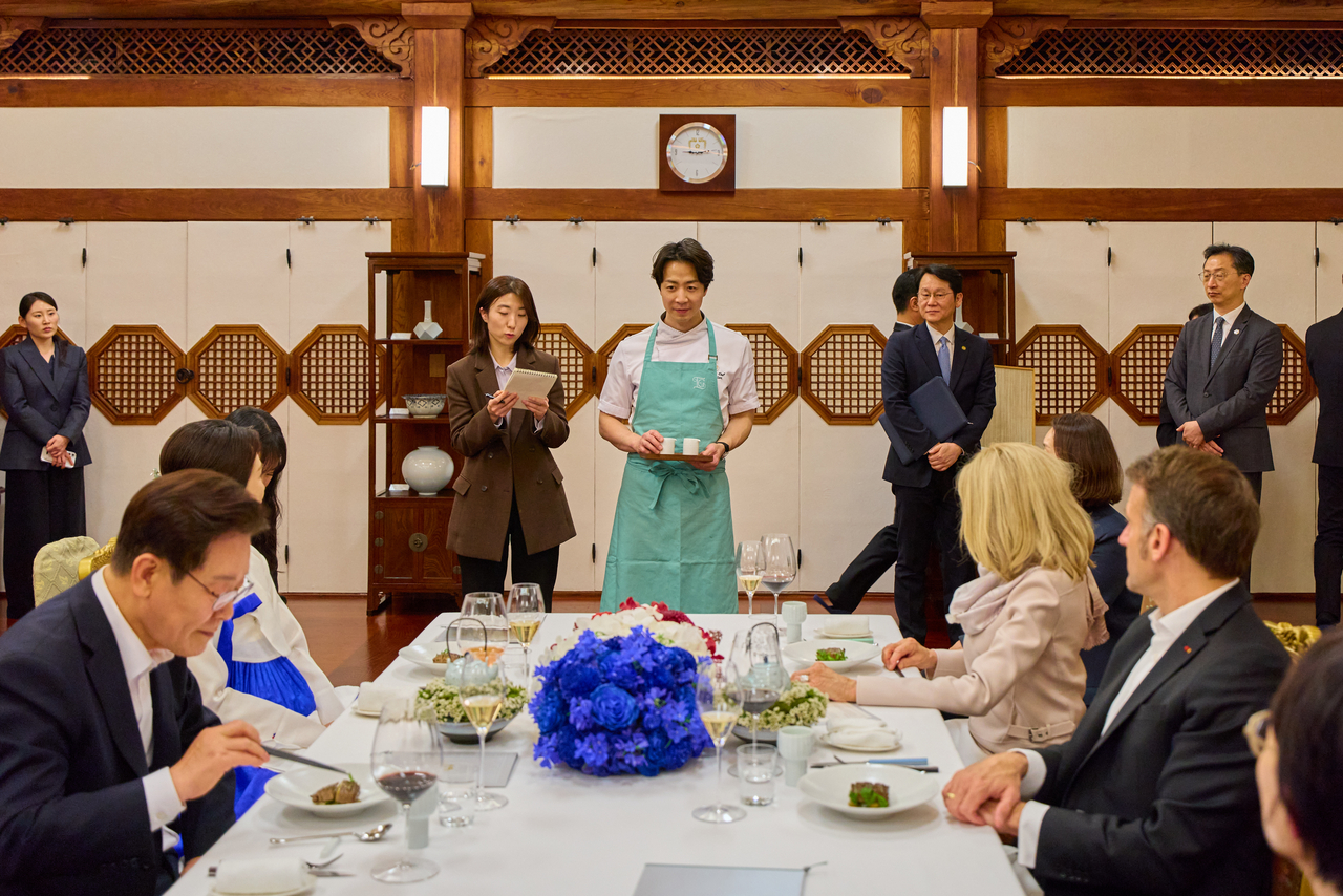 President Lee Jae Myung (right) and French President Emmanuel Macron, accompanied by first lady Kim Hea Kyung and Brigitte Macron, listen as chef Son Jong-won introduces the menu during the state banquet at Cheong Wa Dae on Thursday. (Cheong Wa Dae)