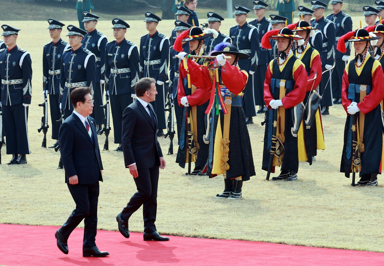 President Lee Jae Myung and French President Emmanuel Macron inspect the honor guard during an official welcoming ceremony at Cheong Wa Dae in Seoul on Friday. (Yonhap)