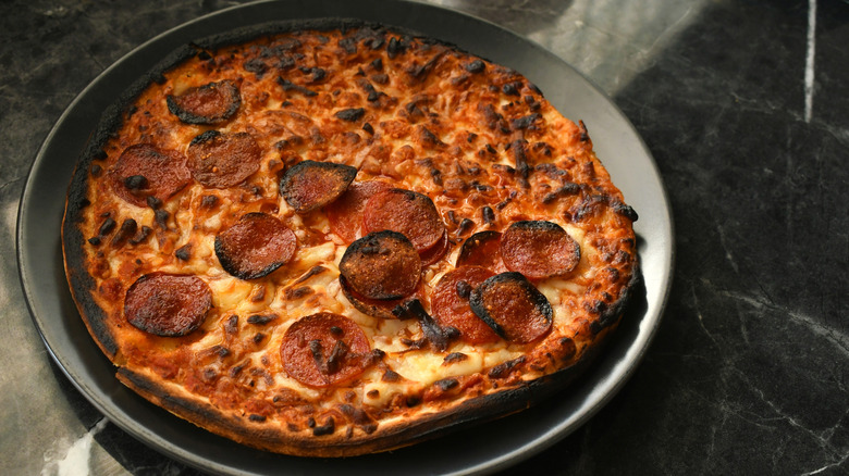 Nearly burnt pizza on grey plate