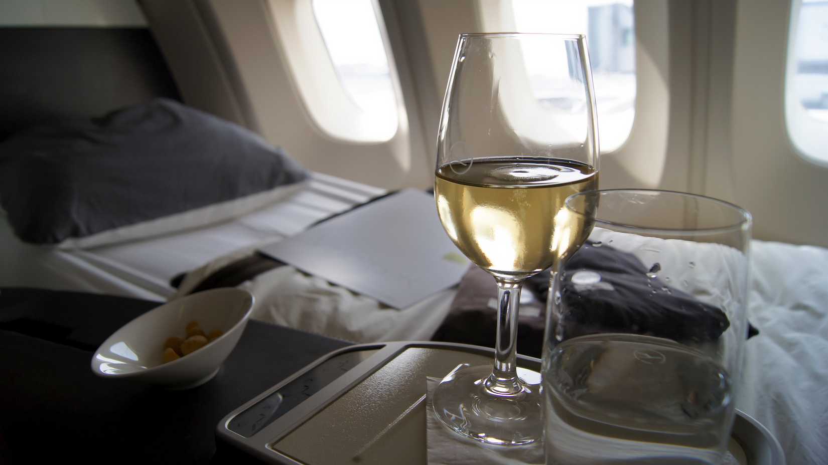  First Class Dining onboard an Boeing 747 upper deck from Lufthansa, white wine, water and nu ts.