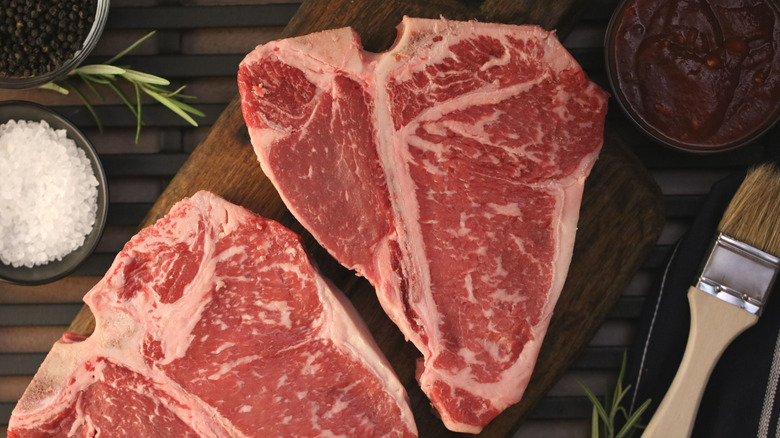 Two raw porterhouse steaks on a cutting board