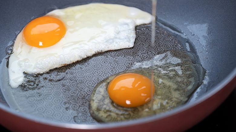 Person cracking egg into frying pan