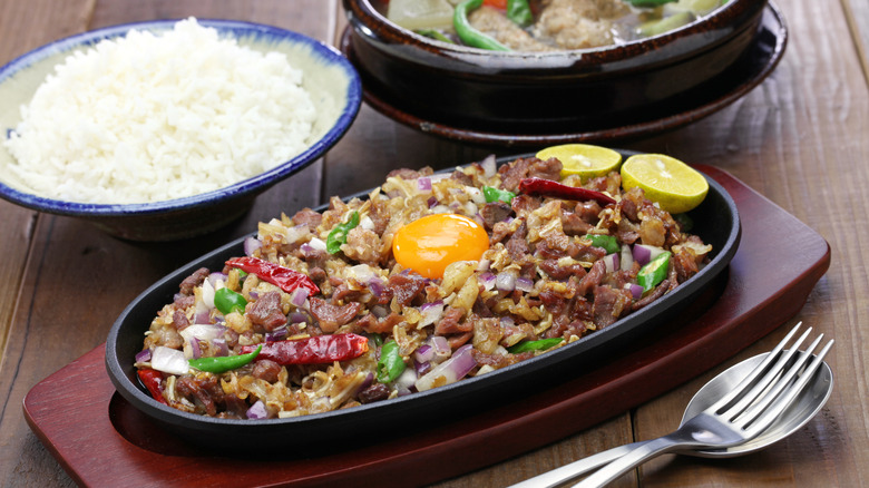 A plate of Filipino sisig with a bowl of white rice