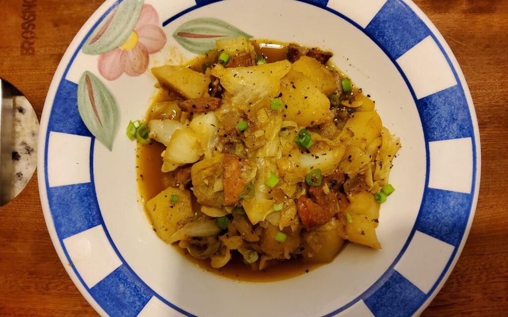 Smothered cabbage and potatoes seasoned with andouille sausage.