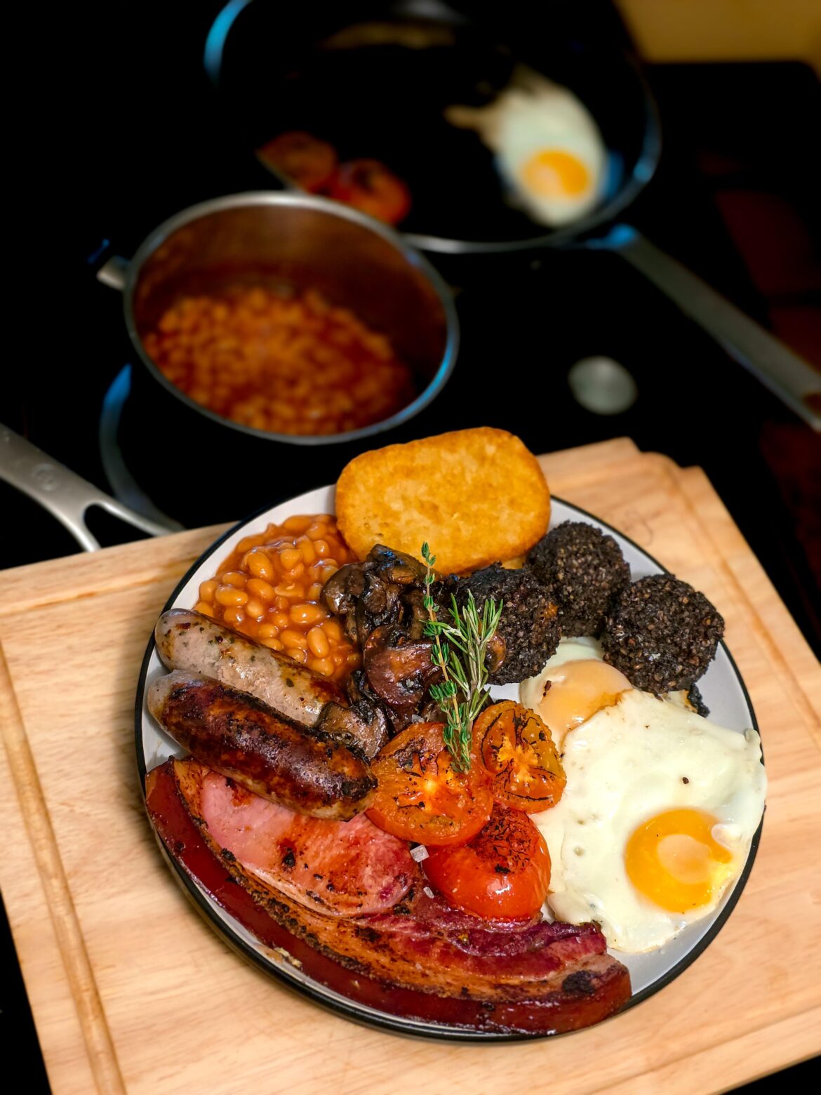 [Homemade] Big breakfast. Bacon chop, fried eggs, onion and sage pork sausage, black pudding, grilled tomatoes, sautéed mushrooms with thyme and balsamic, hash brown, baked beans.