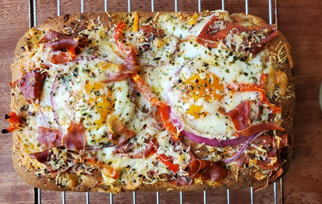 Focaccia breakfast pizza with prosciutto and eggs