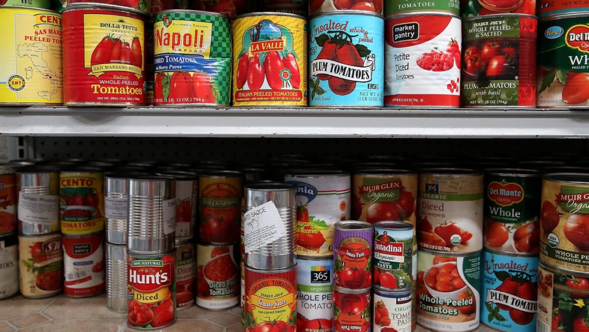 A variety of canned tomato products displayed on a grocery store shelf, including whole, diced, and peeled options.
