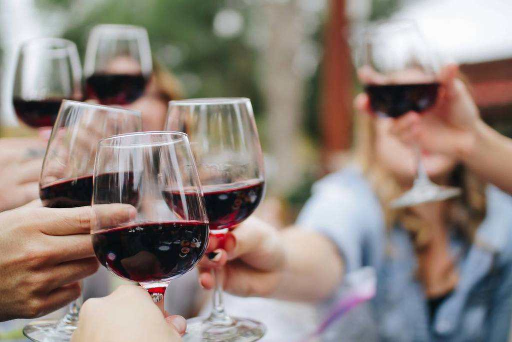 Close up of people clicking red wine glasses during a wine tasting