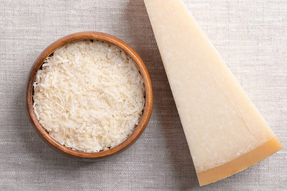 grated parmesan cheese, parmigiano reggiano or grana padano in a wooden bowl on linen