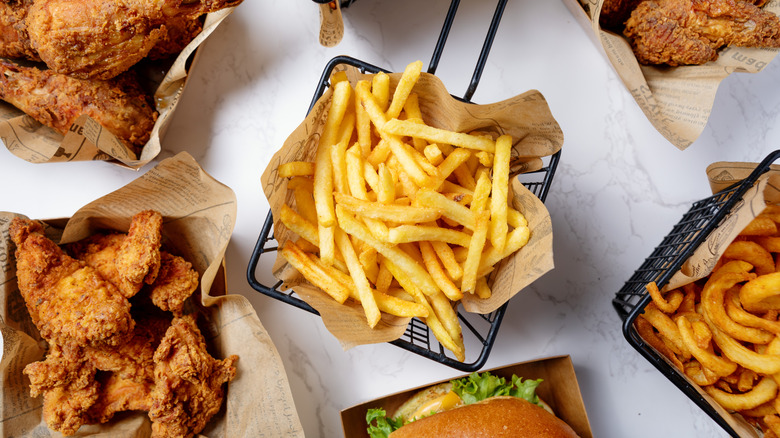 french fries surrounded by fried chicken onion rings and burger
