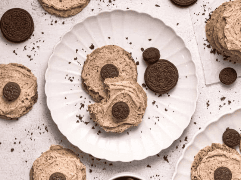 Copycat Crumbl Cookies and Cream Milkshake Cookies arranged on white plates and a light surface with cookie crumbs scattered around.