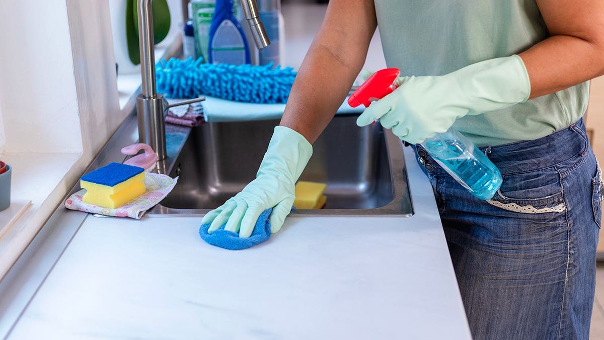 A woman cleaning a kitchen counter with a cloth