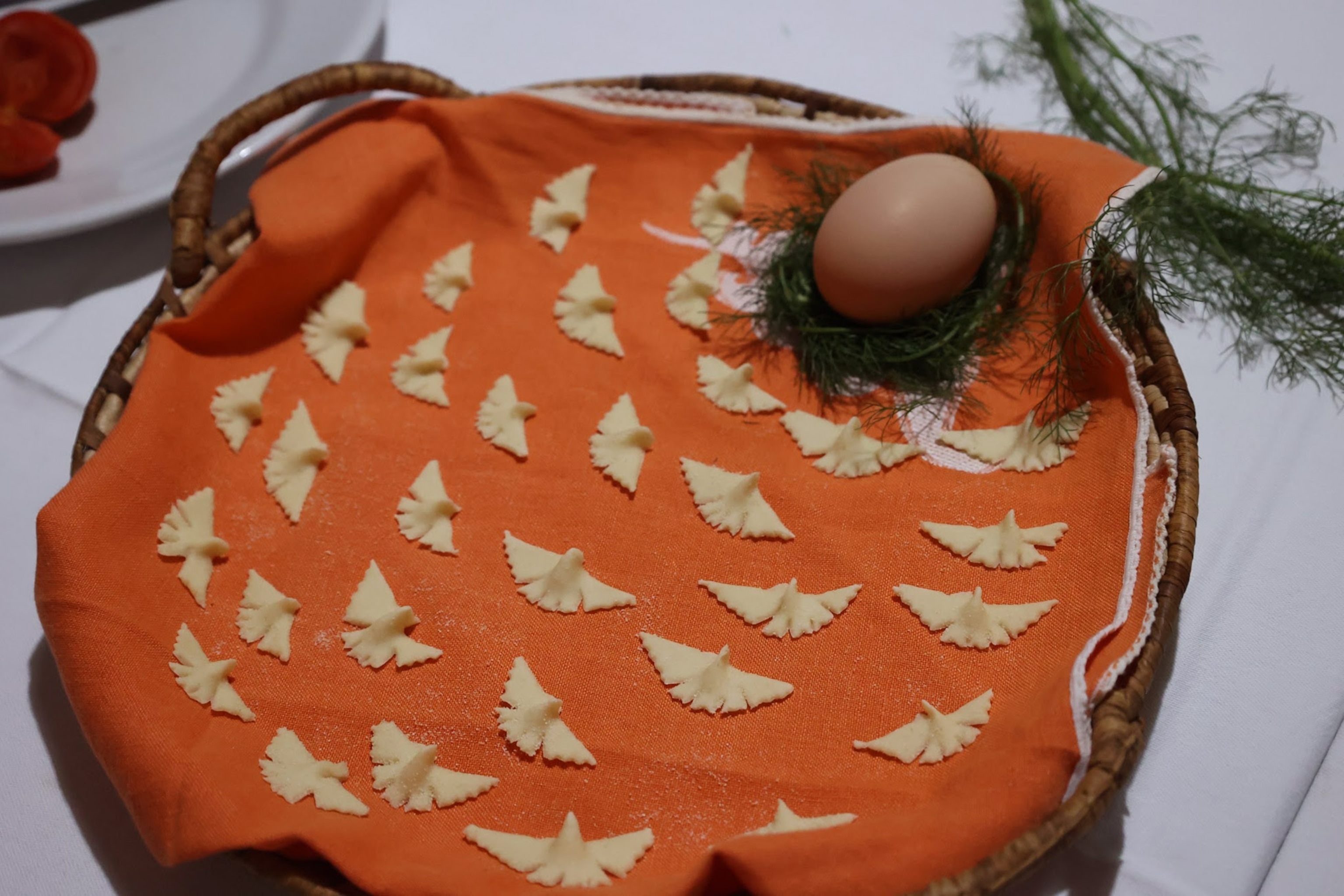 bird-shaped pastas on orange cloth with egg and dill