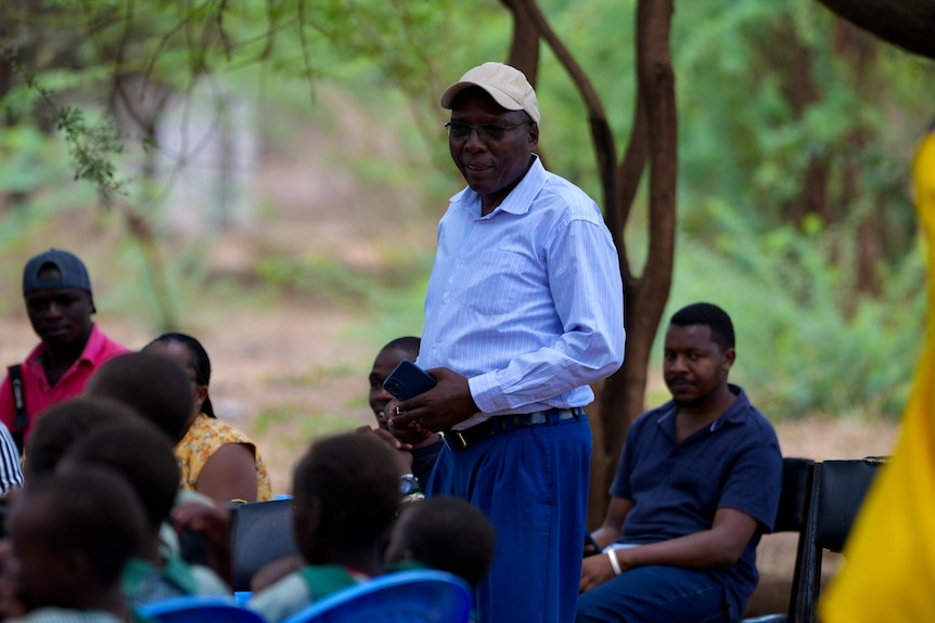 A man addresses a group of students in rural Kenya.