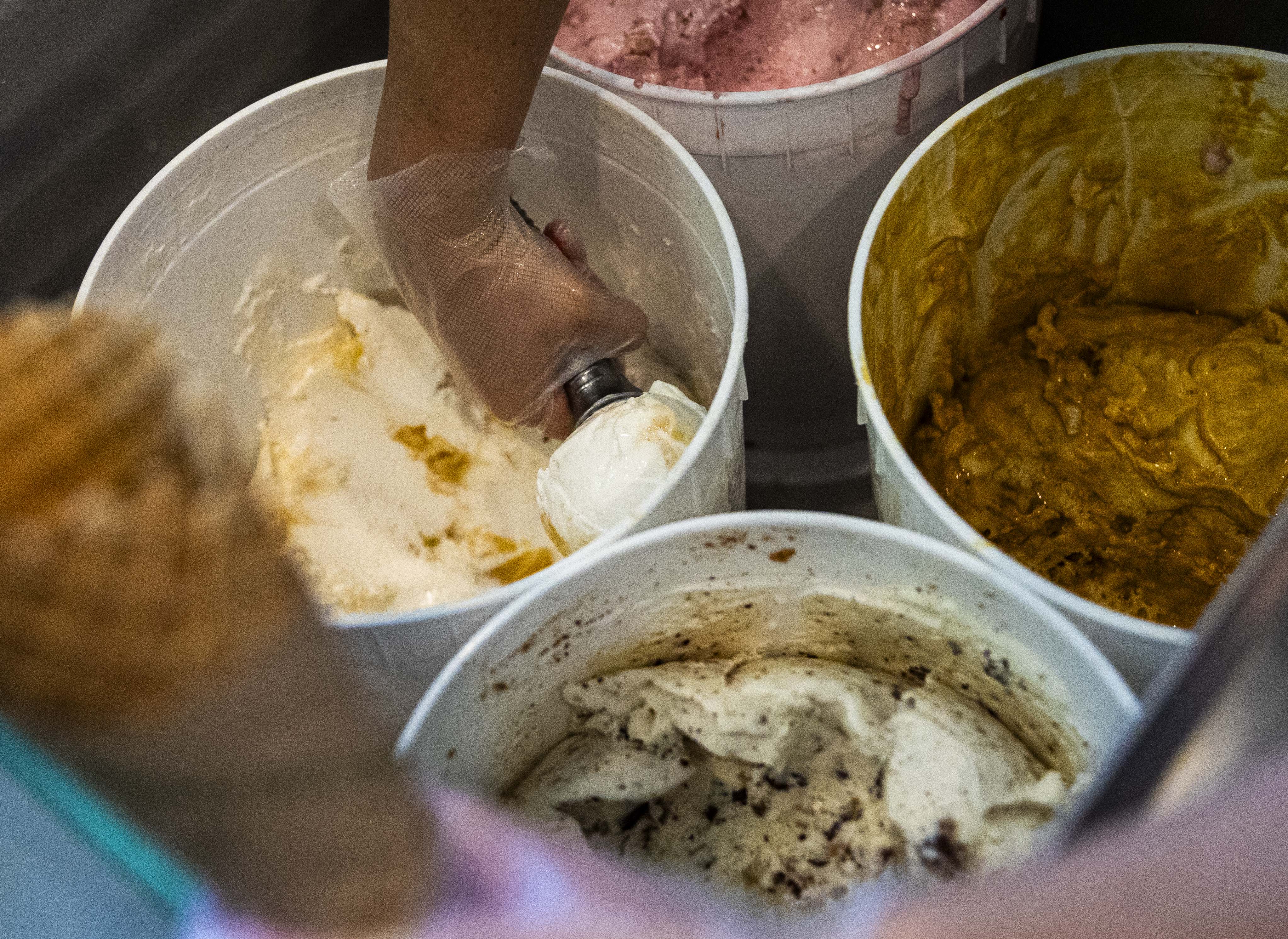 A worker scoops ice cream at Edison's Ice Cream in...