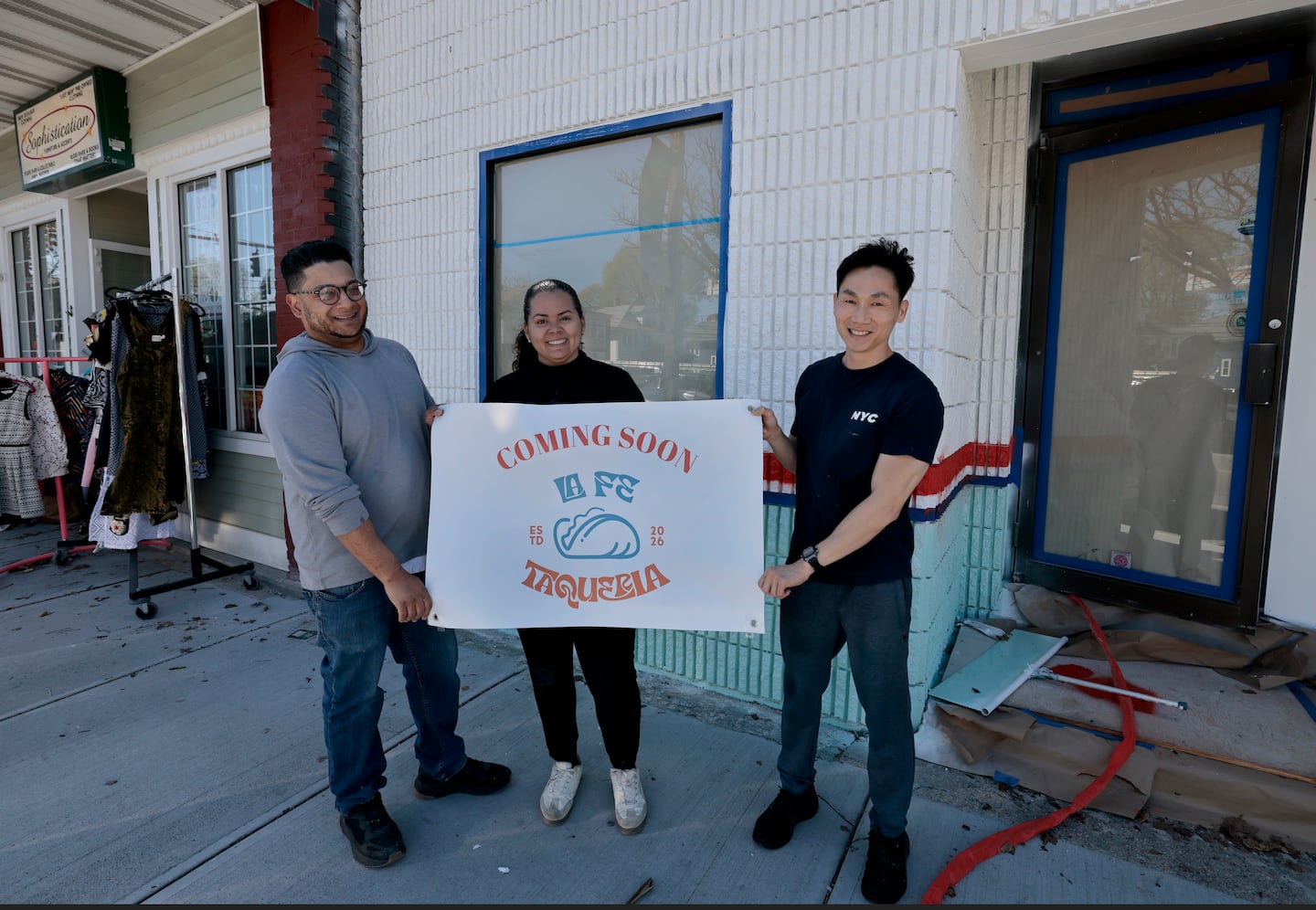 La Fe Taqueria co-owner and operator Jason Vargas (left), manager Melisa Sanchez (center), and co-owner Thang Huynh (right) hold a temporary sign outside of their building on Hope Street in Providence.
