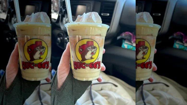 A hand holding Buc-ee's large banana pudding cup in a car