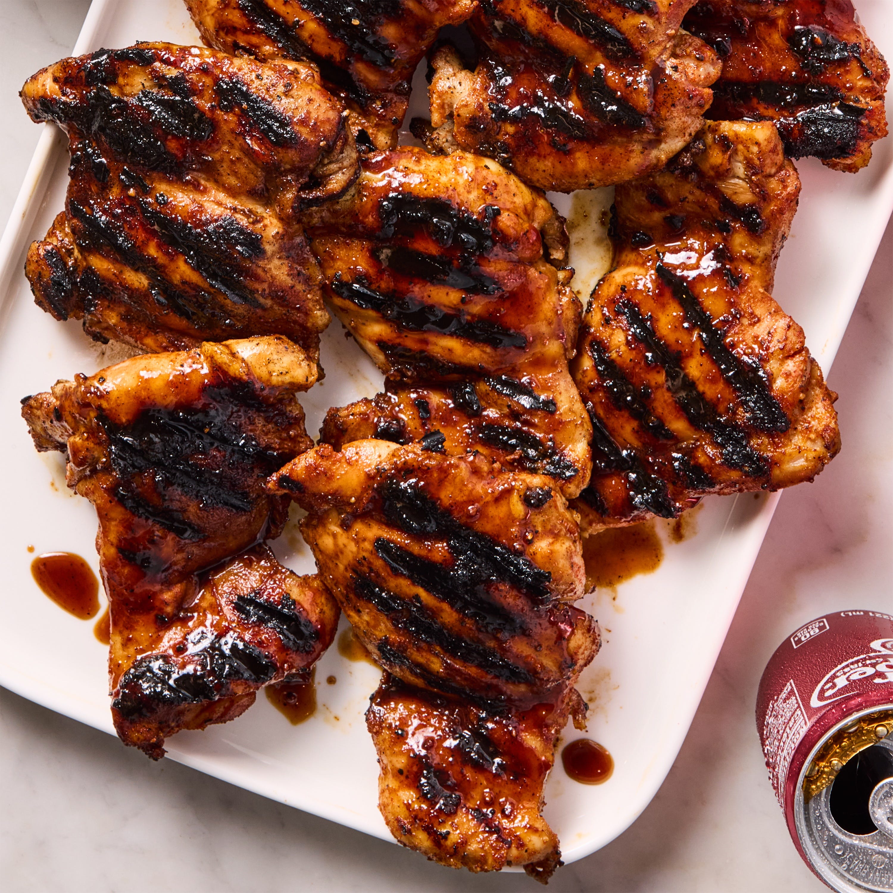 Grilled chicken thighs with barbecue glaze on a white platter.