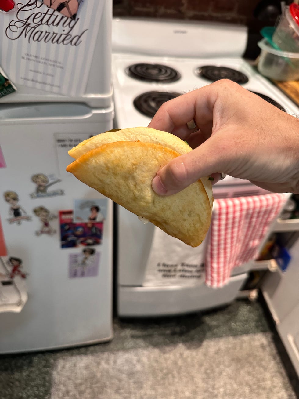 Hand holding a folded taco in a kitchen setting. Hand holding a folded taco in a kitchen setting.