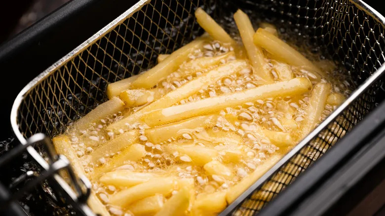 French fries frying inside hot oil in a deep fryer
