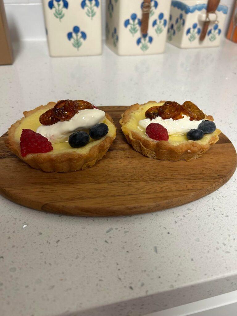 White Chocolate Mascarpone Cheesecake Tart with a Honey Crust - Topped with Candied Kumquats, Whipped Cream, and Berries
