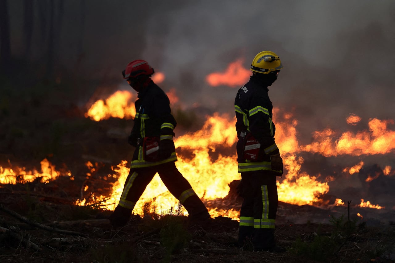 Firefighters work amid flames.