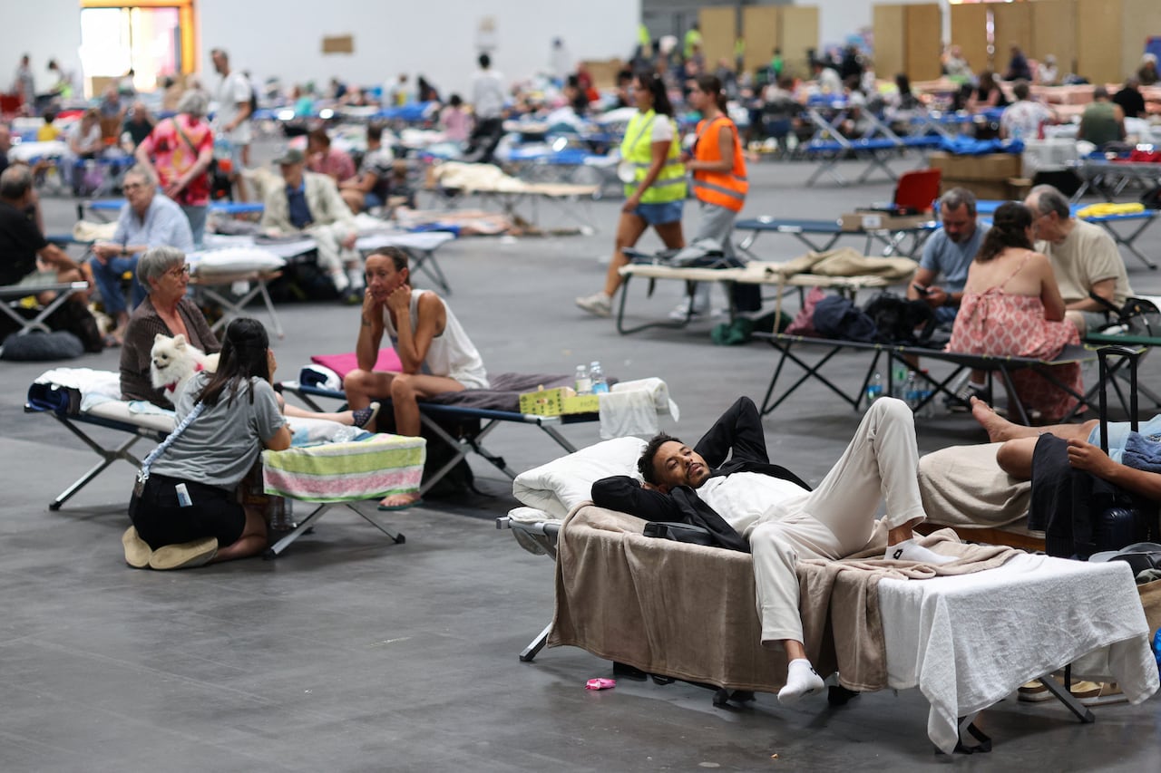 People rest in beds in a large room.