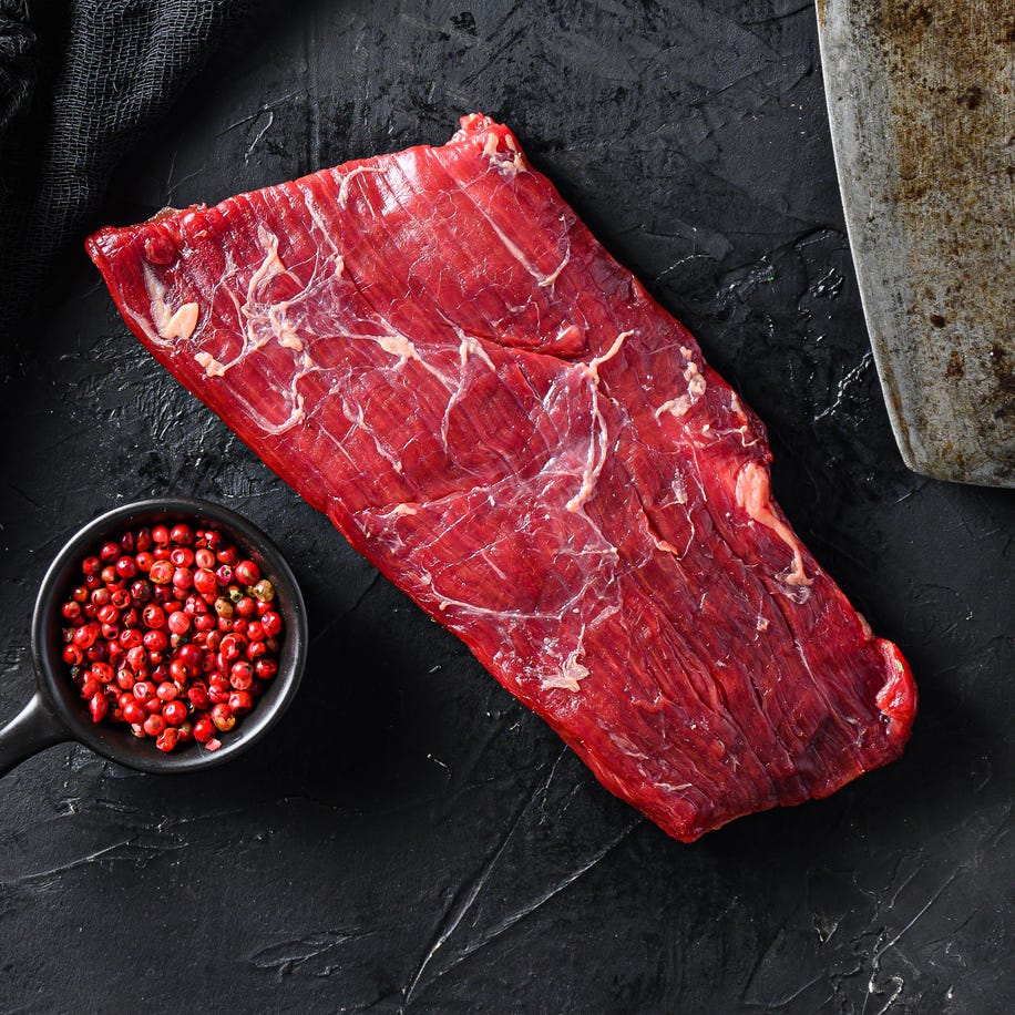 Raw, flap or flank, also known Bavette steak near butcher knife with pink pepper and rosemary. Black background. Top view Raw, flap or flank, also known Bavette steak near butcher knife with pink pepper and rosemary. Black background. Top view