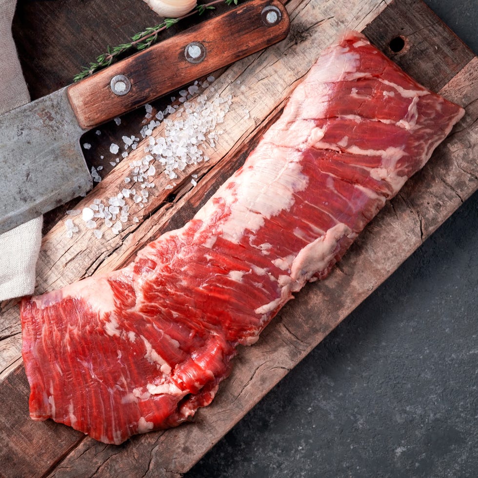 Raw beef machete steak with meat axe on a wooden Board with seasoning. Stone background. Raw beef machete steak with meat axe on a wooden Board with seasoning. Stone background.
