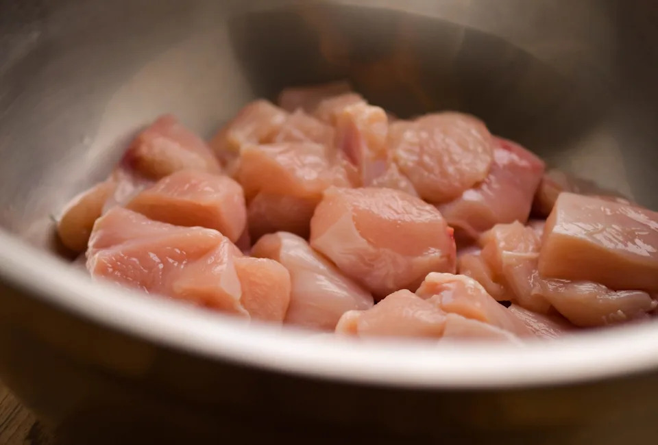 Diced raw chicken in a metal bowl, ready for cooking or meal preparation