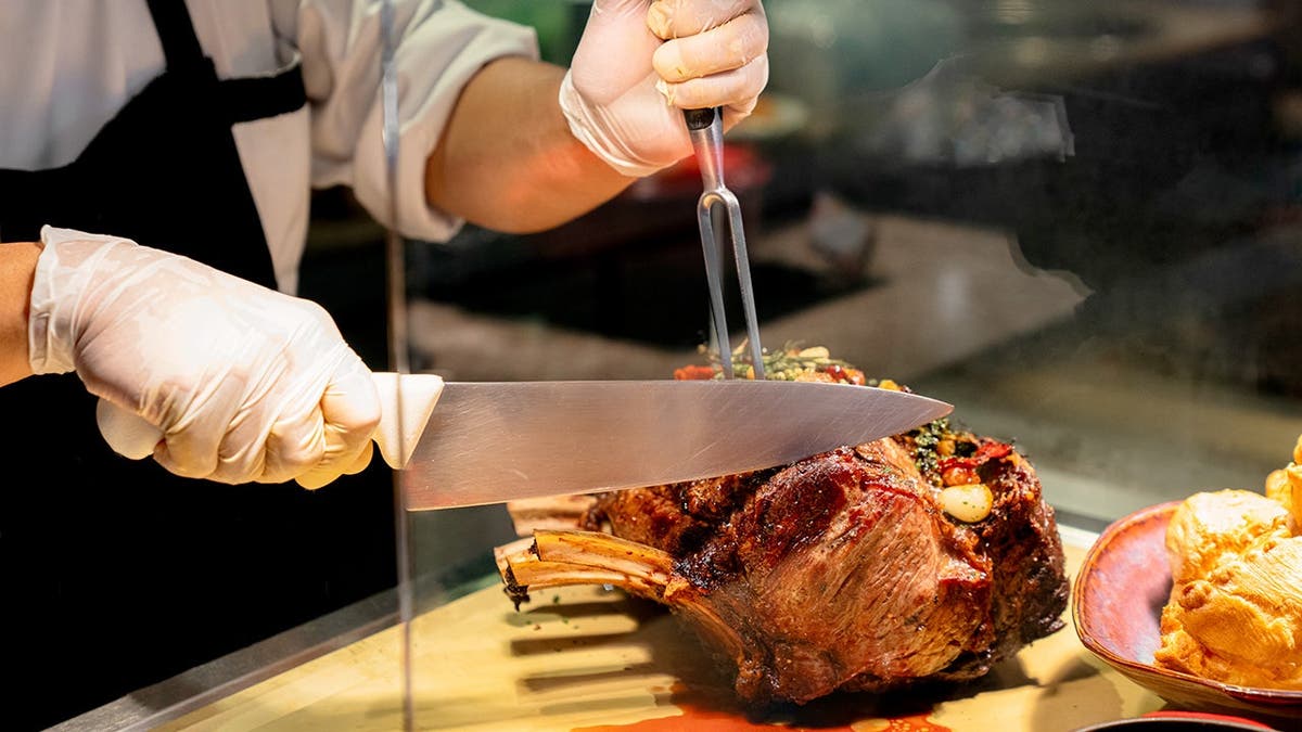 A chef cuts a slice of prime rib.