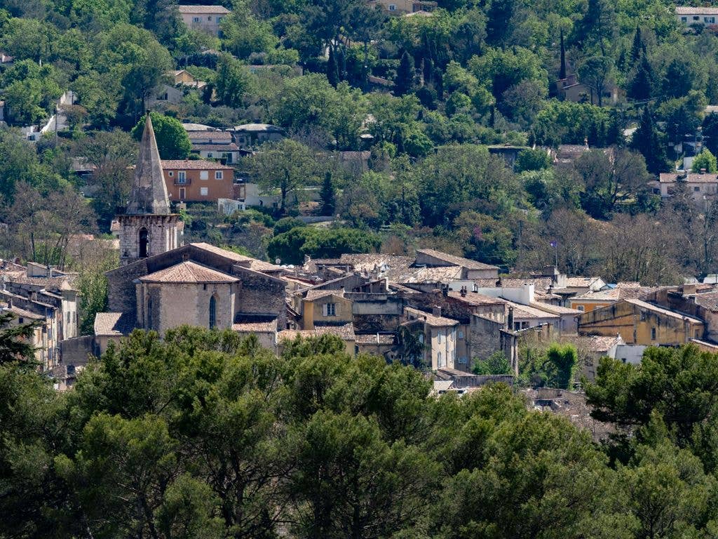 Aerial view of a village with a prominent church tower, surrounded by trees and houses.